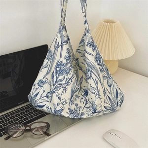 Blue and white floral canvas tote bag on a minimalist desk with lifestyle accessories