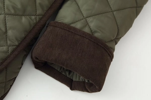 Détail de la manche de veste matelassée verte avec poignet en velours côtelé marron