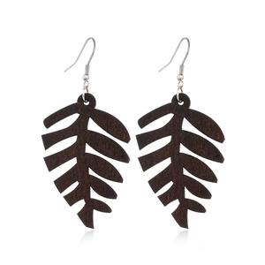 Close-up of leaf-shaped hollowed wooden earrings with metallic hooks in natural style