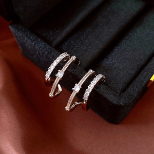 Detailed macro of C-shaped silver earrings with sparkling cubic zirconia on dark silk background