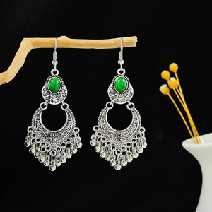 Détail de boucles d'oreilles bohèmes avec pierre turquoise et perles argentées sur branche