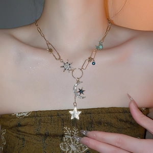 Détail du collier asymétrique avec pendentifs étoile et lune sertis de cristaux bleus