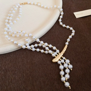 Detail of multi-layer pearl necklace with golden charm on beige plate and fur background