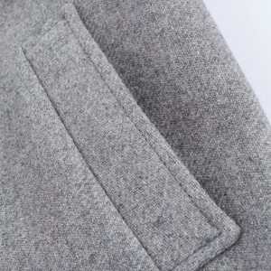 Macro shot of gray wool coat pocket showing precise stitching and tweed texture details