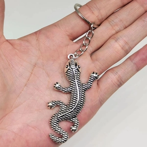 Detailed close-up of a silver gecko lizard keychain with textured metal relief finish