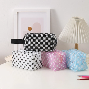 Detail of four checkered and heart pattern PVC pencil cases with handles and zippers