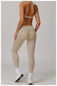Detail of high waist yoga leggings and cross-strap sports bra in beige seamless fabric