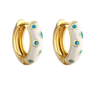 Detail of gold hoop earrings with white enamel coating and delicate blue floral patterns