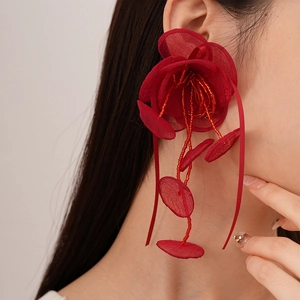Détail de boucles d'oreilles fleurs en dentelle rouge avec de longs pompons perlés