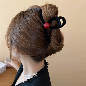 Detail of elegant black velvet hair claw clip with a single red bead accent on model