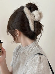 Détail de la pince à cheveux en peluche beige portée par un modèle pour montrer le style