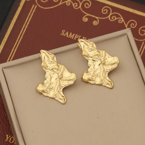 Detailed macro view of gold irregular geometric stud earrings with textured finish