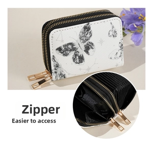 Détail du porte-cartes en accordéon avec double zip, motif papillon et ferrures dorées