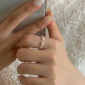 Minimalist S925 sterling silver heart-shaped ring worn on finger over white soft fabric
