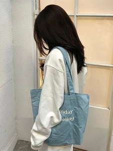 Borsa tote in tela blu con ricamo Monday Feeling mostrata a tracolla su una modella