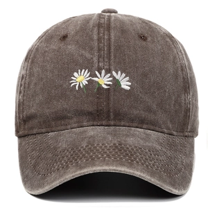Dettaglio di piccole margherite ricamate su un cappellino da baseball in cotone marrone