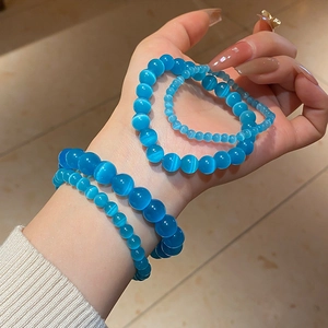 Detailed view of blue cat-eye stone bracelets showing chatoyancy effect on a woman's wrist