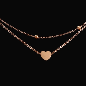 Detail van de roségouden dubbellaagse enkelband met hartjes hanger en kleine kralen