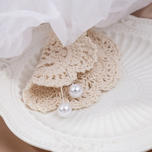 Detail of round white pearl earrings with silver posts on a decorative ceramic tray