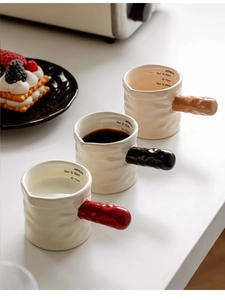 Detailed view of ceramic espresso milk pitchers with colored handles and scale markings