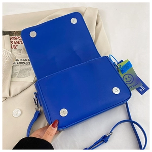 Detail of bright blue faux leather handbag with silver magnetic buckles and shoulder strap