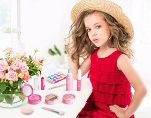 Detailed view of pink pretend makeup kit with eyeshadow, lipstick and brushes for kids
