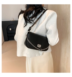 Vue latérale du sac à bandoulière en cuir noir avec chaîne argentée et fermoir sur modèle