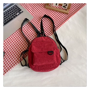 Detail of red corduroy backpack showing top-down view on a plaid background