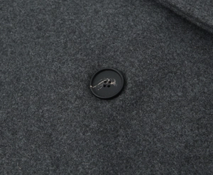 Vue rapprochée du tissu en laine gris foncé et d'un bouton aux motifs marbrés