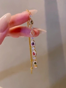 Close-up of gold chain bracelet featuring colorful teardrop-shaped zircon gemstones