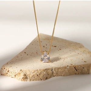 Detail of 18k gold plated necklace with teardrop white zircon pendant on stone