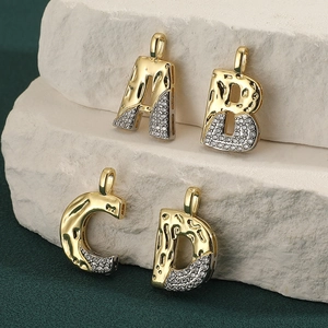 Two-tone alphabet letter pendants A B C D with cubic zirconia on white stone background
