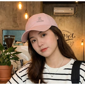 Gros plan d'une casquette de baseball rose respirante avec logo métallique au café
