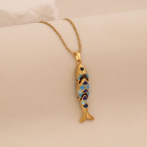 Macro detail of golden fish pendant with blue enamel craft on beaded chain necklace
