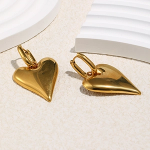 Dettaglio di pendenti a cuore dorati lucidi su orecchini a cerchio minimalisti chic