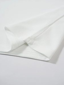 Gros plan détaillé sur le tissu gaufré blanc et les coutures de qualité sur l'ourlet