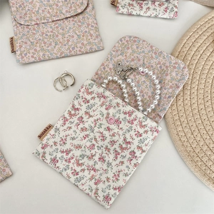 Flat lay of floral cotton storage bags with pearls and accessories on white background