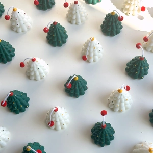 Detail view of handmade mini Christmas tree candles in green and white with red toppers