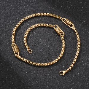 Detail einer goldenen Venezianerkette mit Federakzenten und Karabinerverschluss auf dunklem Grund