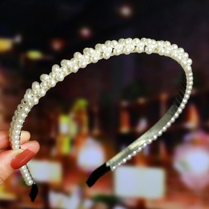 Detailed close-up of woven white pearls on a slim headband with anti-slip protective tips