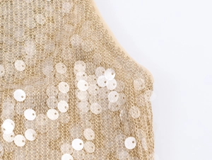 Macro detail of gold metallic lace fabric with white circular sequins and neat stitching
