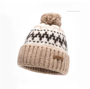 Detailed texture of khaki knitted winter hat with jacquard pattern and fluffy pom-pom top