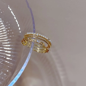 Detail of gold multi-layer ring featuring delicate pearls and sparkling zircon accents