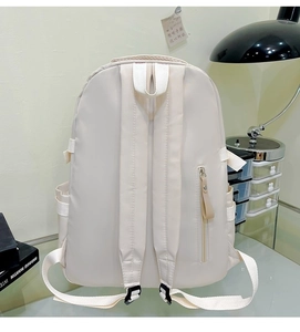 Detail view of cream white backpack featuring a hidden anti-theft zipper pocket on the back