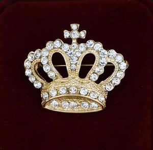 Detail of a vintage golden crown brooch with sparkling rhinestones on red velvet