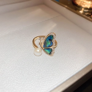 Detail of gold butterfly ring with pearl and abalone shell inlay on a jewelry box
