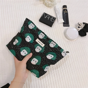 Detail of canvas pouch with green girl pattern and Simple Wish label among cosmetics