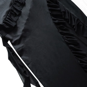 Close-up of black dress featuring ruffle trim and sheer mesh patchwork details