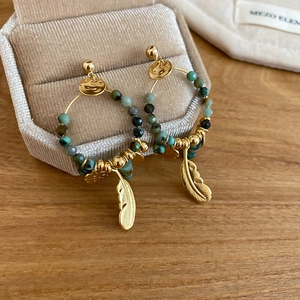 Macro shot of 14K gold plated feather earrings with turquoise beads on velvet box