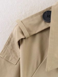 Detail shot of khaki trench coat epaulette with heavy twill fabric and resin button